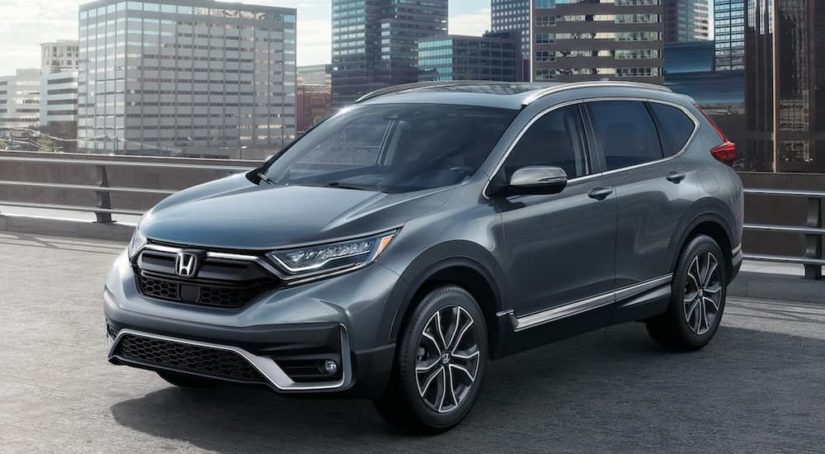 A dark grey 2021 Honda CR-V is parked on an overpass in front of a city.