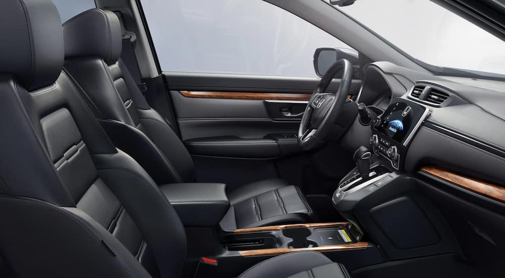 The interior of a 2021 Honda CR-V shows the front seats, steering wheel, and infotainment screen.