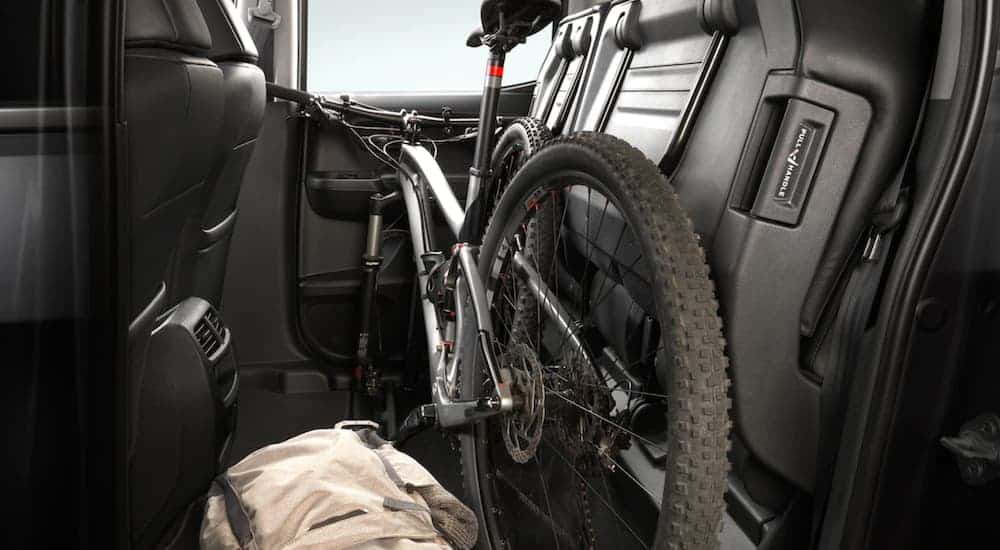 A bike is shown stored in the folded back seat area of a 2021 Honda Ridgeline RTL-E.