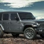 A grey Jeep Wrangler is parked in front of mountains after a buyer reviewed the Jeep Wrangler buyer's guide.