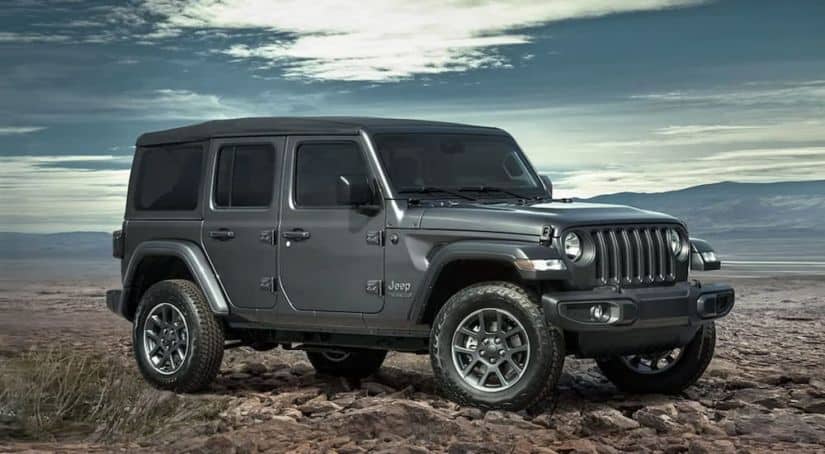 A grey Jeep Wrangler is parked in front of mountains after a buyer reviewed the Jeep Wrangler buyer's guide.