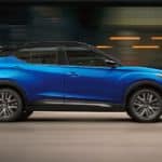 A blue 2021 Nissan Kicks is shown from the side driving through the city.