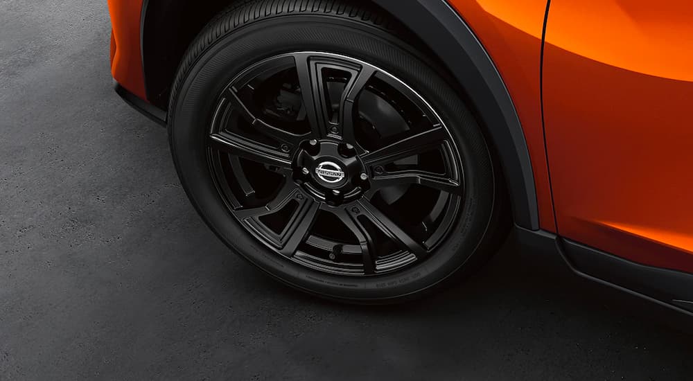 A close up shows the black alloy wheel on an orange 2021 Nissan Kicks.