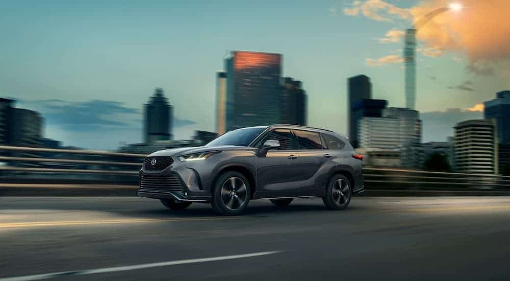 A gray 2021 Toyota Highlander XSE is shown from the side driving through a city.
