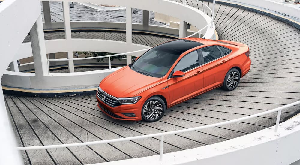 An orange 2021 Volkswagen Jetta is driving down a ramp.