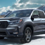 A 2021 Honda Ridgeline is parked in the snow in front of mountains after leaving a Honda Ridgeline Dealership.