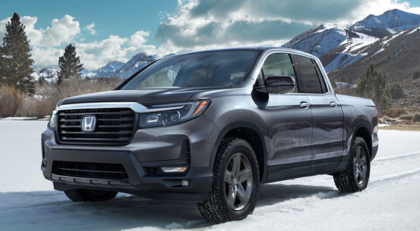 A 2021 Honda Ridgeline is parked in the snow in front of mountains after leaving a Honda Ridgeline Dealership.