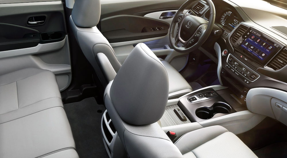 The interior of a 2021 Honda Ridgeline shows two rows of seating, the steering wheel and infotainment screen.