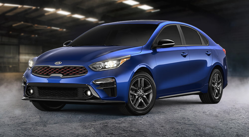 A blue 2021 Kia Forte is parked in a warehouse.