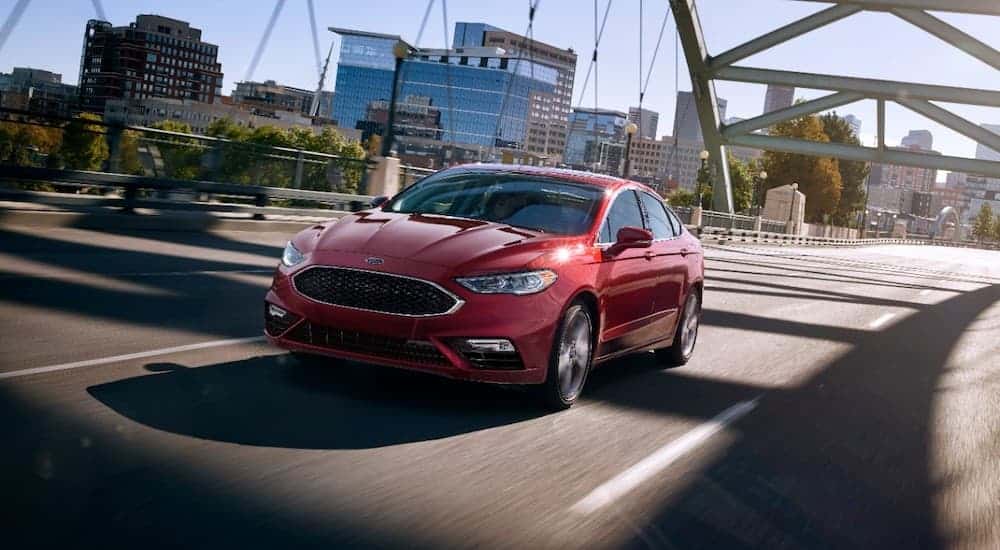 A red 2017 Ford Fusion is shown driving over a steel bridge.