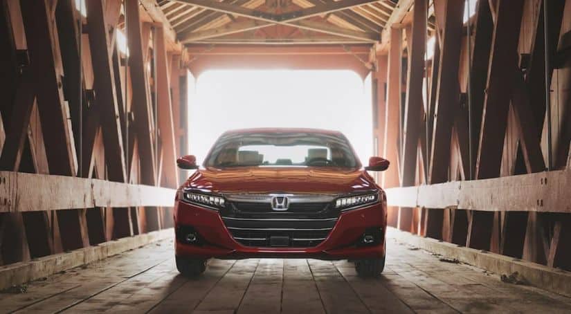 A popular used family car, a red 2021 Honda Accord, is parked on a covered wooden bridge.