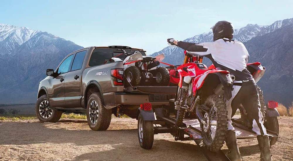 A gray 2020 Nissan Titan Pro 4X is shown from the rear with a dirt bike being loaded on its trailer.