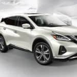 A white 2021 Nissan Murano is shown angled right against a faded city background.