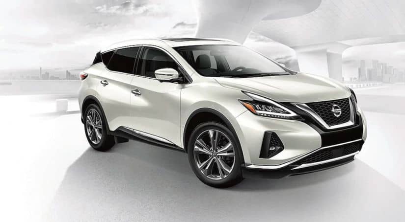 A white 2021 Nissan Murano is shown angled right against a faded city background.