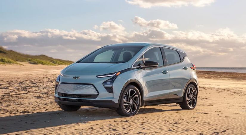 A light blue 2022 Chevy Bolt EV is parked on a beach after leaving the electric car dealer.