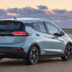 A light blue 2022 Chevy Bolt EV is parked on a beach after leaving an electric car dealer.