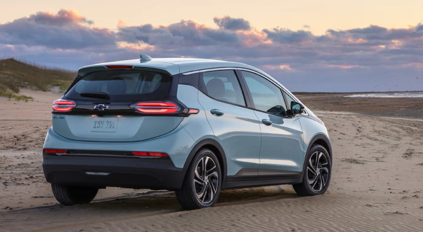 A light blue 2022 Chevy Bolt EV is parked on a beach after leaving an electric car dealer.