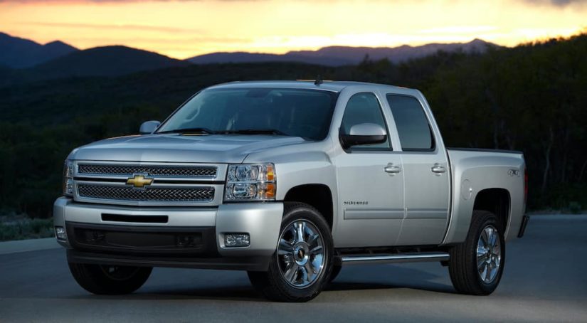 A silver 2012 Chevy Silverado LTZ is parked in front of a mountain at sunset after leaving a used Chevy Silverado 1500 dealer.