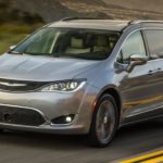 A grey 2017 Chrysler Pacifica is driving down a two way road as the perfect used family car.