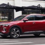 A red 2021 Buick Envision is driving on a city street after winning the 2021 Buick Envision vs 2021 Acura RDX comparison.