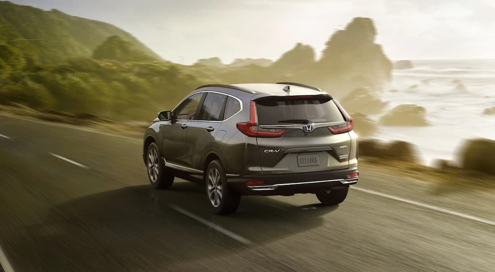 A silver 2021 Honda CR-V Hybrid Touring is driving past a lake.