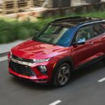 A red 2021 Chevy Trailblazer is shown from the side as it drives through a city.