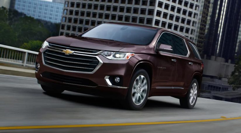 A maroon 2021 Chevy Traverse is shown from an angle driving through a city.