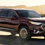 A maroon 2021 Chevy Traverse is driving down a desert road after winnning a 2021 Chevy Traverse vs 2021 Honda Pilot comparison.
