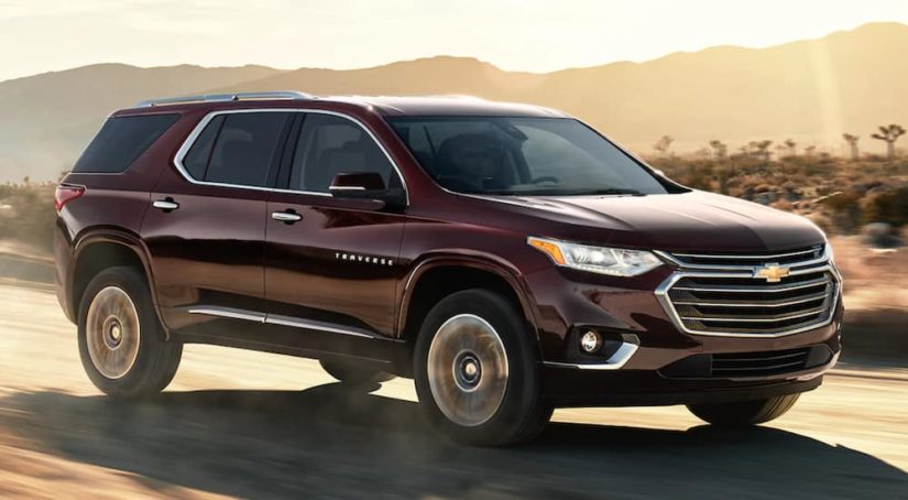 A maroon 2021 Chevy Traverse is driving down a desert road after winnning a 2021 Chevy Traverse vs 2021 Honda Pilot comparison.