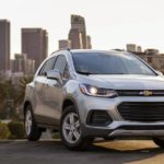 A silver 2021 Chevy Trax is shown from the side parked on top of a city hill.