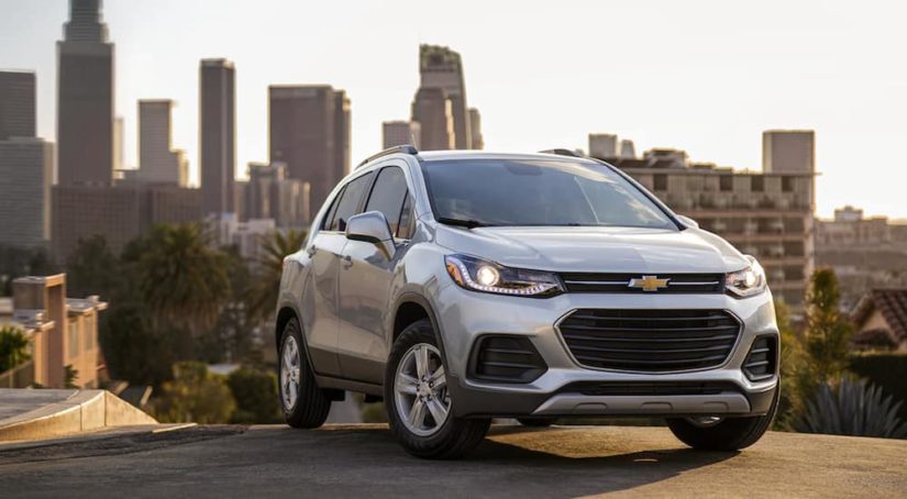 A silver 2021 Chevy Trax is shown from the side parked on top of a city hill.