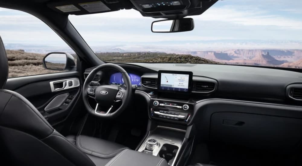 The interior of a 2021 Ford Explorer shows a steering wheel and infotainment screen. 