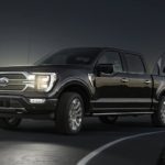 A black 2021 Ford F-150 is towing a camper after winning a 2021 Ford F-150 vs 2021 Ram 1500 comparison.