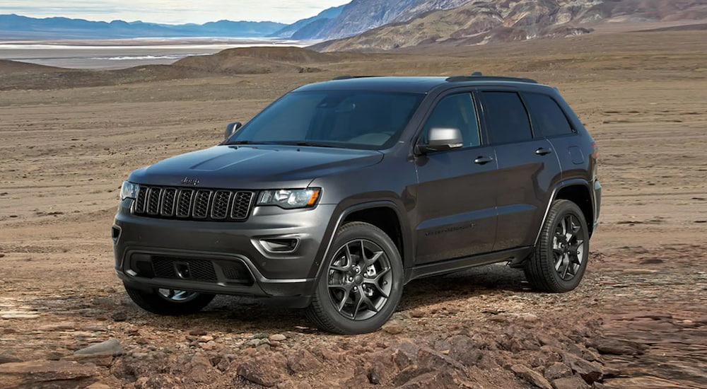 A grey 2021 Jeep Grand Cherokee is parked at the base of a mountain.