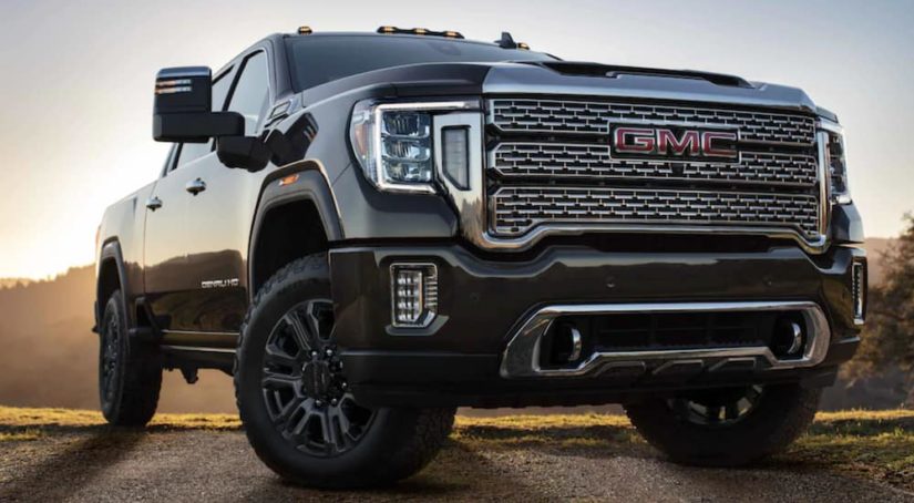 A black 2021 GMC Sierra 2500 is shown from a low angle parked on a patch of dirt.