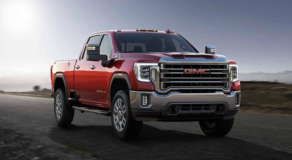 A red 2021 GMC Sierra 2500 is shown driving on an open road.