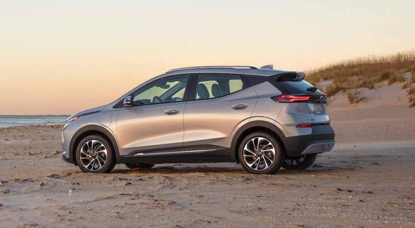 A silver 2022 Chevy Bolt EUV is parked on the beach at sunset.