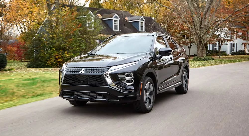 A black 2022 Mitsubishi Eclipse Cross is driving through a residential area.
