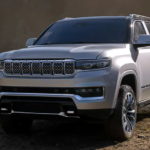 A white 2022 Wagoneer is parked in a dirt field.
