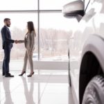 A man and woman are shaking hands at a Buy Here Pay Here dealership.