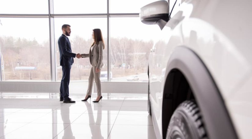 A man and woman are shaking hands at a Buy Here Pay Here dealership.