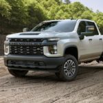 A Certified Pre-Owned Chevy white 2020 Chevrolet Silverado 2500HD is parked at a construction site.