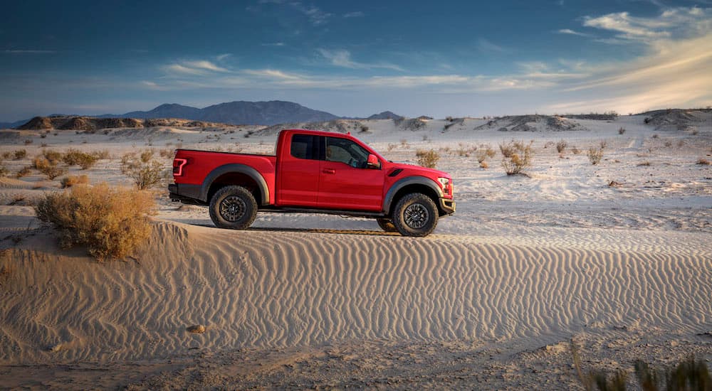 A red 2019 Certified Pre-Owned Ford F-150 Raptor is driving off road in the desert.