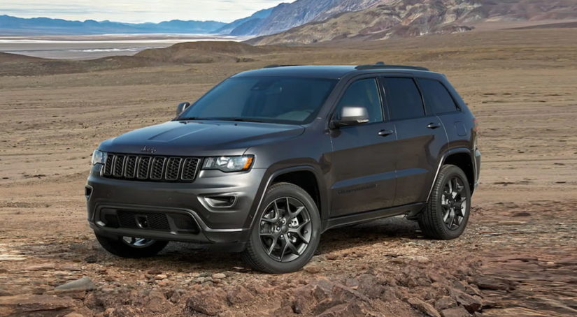 A dark grey 2021 Certified Pre-Owned Jeep Grand Cherokee is parked at the base of a mountain.