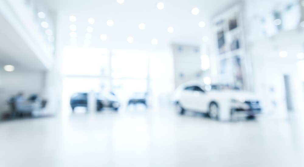 A blurred showroom shows multiple cars.