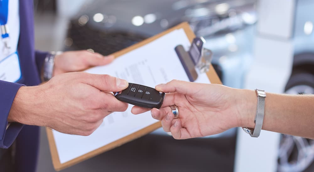 A woman is passing her key to a salesman at a Ford end of lease deal.