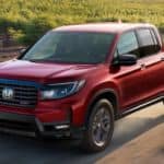 A red 2021 Honda Ridgeline drives through a dusty vineyard after leaving a Honda Ridgeline dealer.