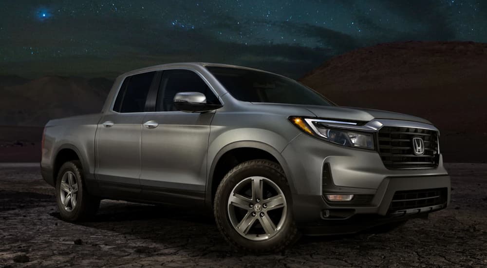 A silver 2021 Honda Ridgeline is parked outside at night.