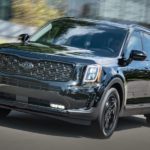 A black 2021 Kia Telluride is driving on a city street after leaving a Kia Telluride dealer.