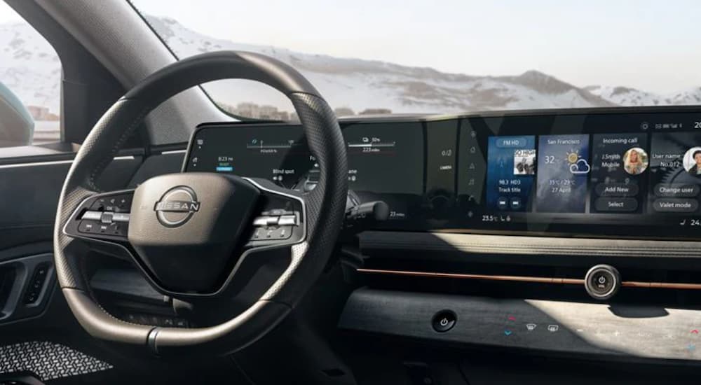The interior of a 2021 Nissan Ariya shows the steering wheel and infotainment screen.